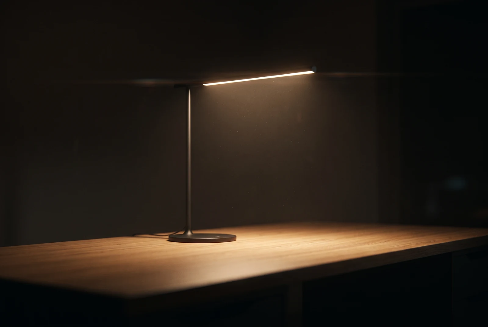 Eine schlanke moderne Lampe leuchtet über einem leeren Schreibtisch